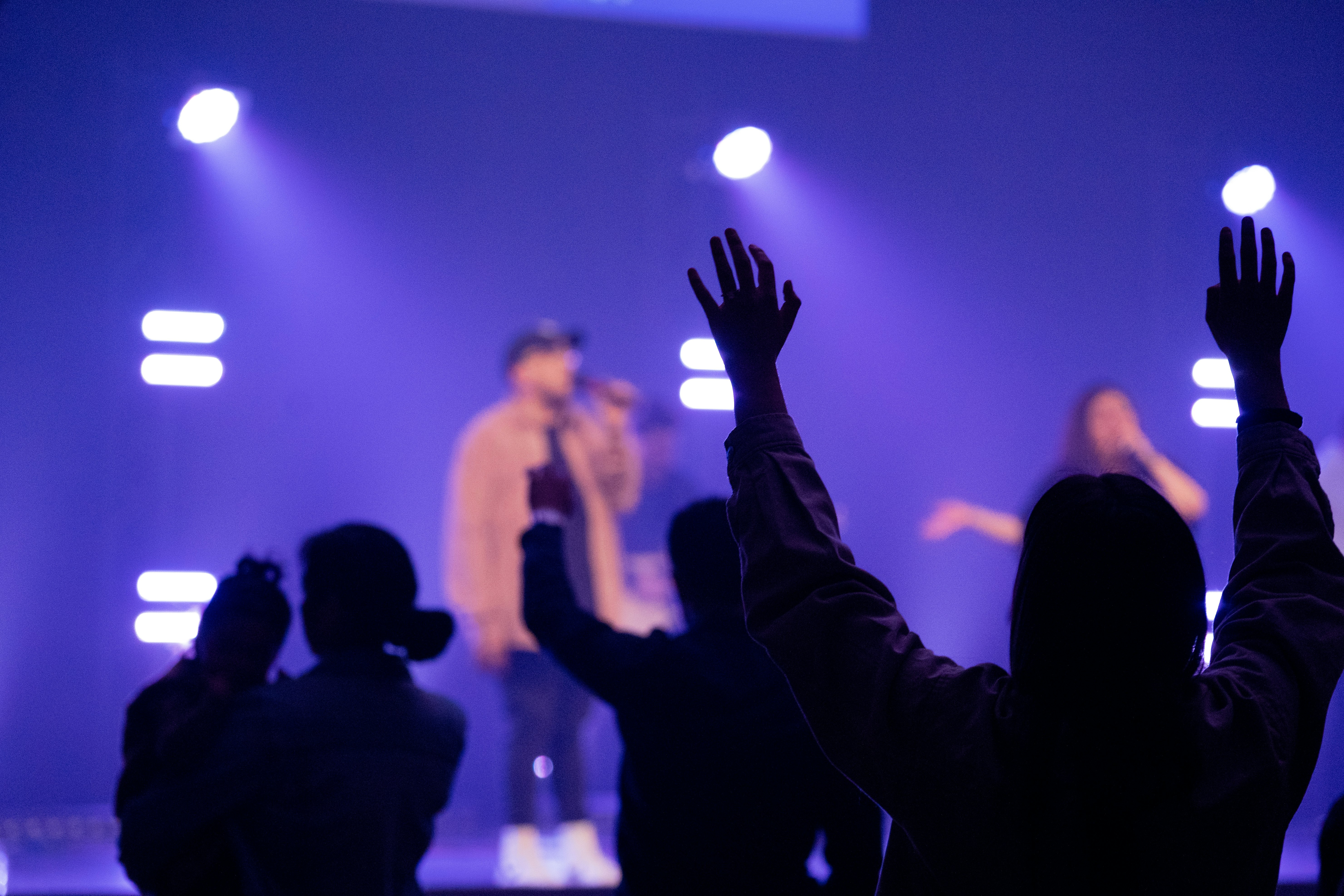 people raising their hands in front of a concert